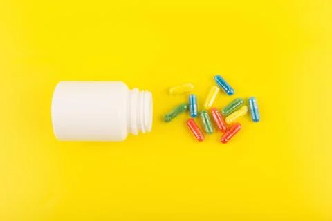 Flat lay with white medication bottle with spilled multicolored pills against Stock Photos