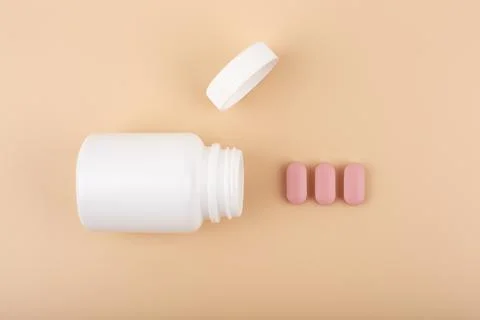 Flat lay with white opened medication bottle with accurately spilled pills Stock Photos