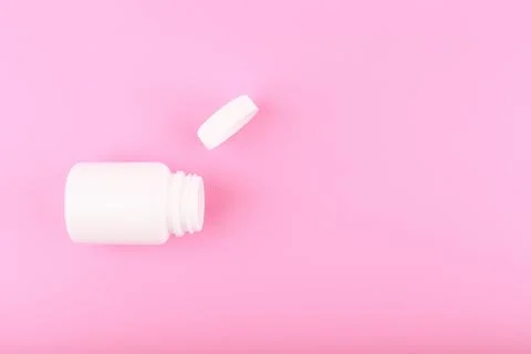 Flat lay with white opened medication bottle on saturated pink background Stock Photos