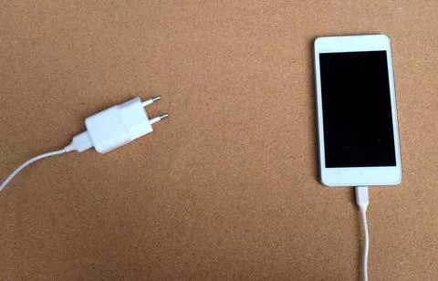 Flat lay white Smartphone Plug In with Charger Adapter on brown Background Stock Photos