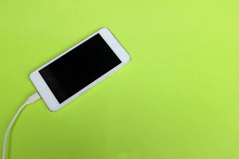 Flat lay white Smartphone Plug In with Charger Adapter on green Background Stock Photos