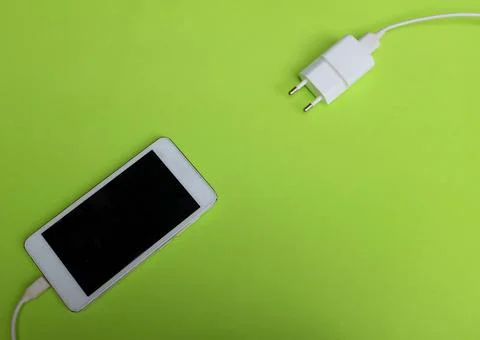 Flat lay white Smartphone Plug In with Charger Adapter on green Background Stock Photos