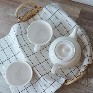 Flat lay of white tea pot and cups on rattan tray Stock Photos