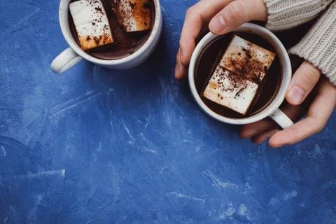 Flat lay of woman's hands in sweater and two cups of cocoa or hot chocolate w Stock Photos