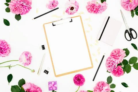 Flat lay work place with clipboard, pink flowers and accessories on white bac Foto stock