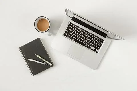 Flat Lay Workspace of Laptop, Coffee, Notepad, Pens, and Pencils - White Mi.. Foto stock