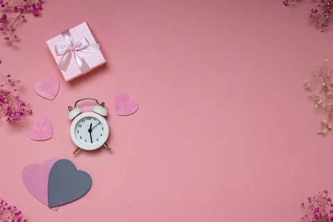 Flat lay workspace on pink background, holiday gifts, alarm clock and hearts Stock Photos