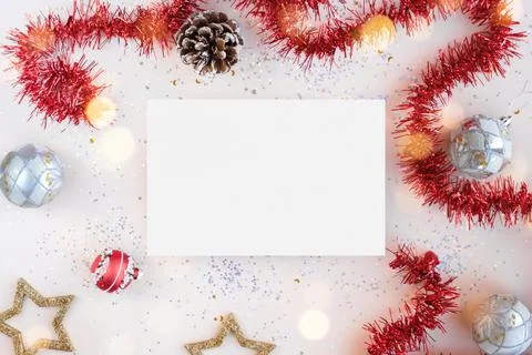 Flat lay xmas composition with isolated white paper. Red tinsel, golden stars Stock Photos