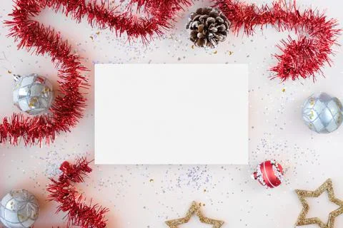 Flat lay xmas composition with isolated white paper. Red tinsel, golden stars Stock Photos
