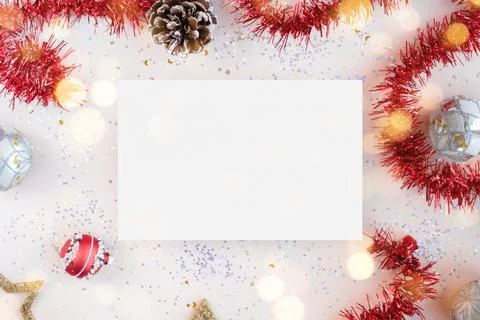 Flat lay Xmas composition with isolated white paper. Red tinsel, golden stars Stock Photos