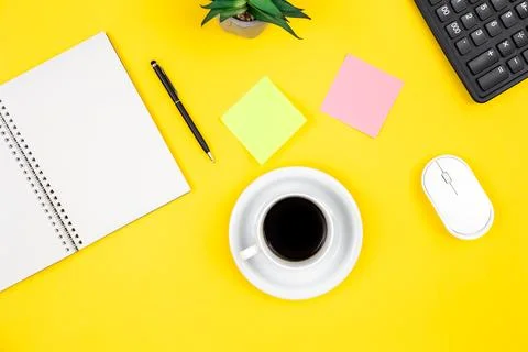Flat lay, yellow background with coffee cup and notepad. Stock Photos
