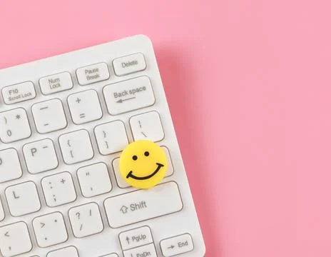 Flat lay of  yellow circle smiling face on white computer keyboard on pink .. Foto stock