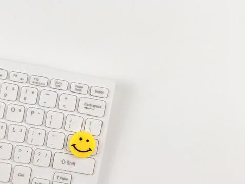 Flat lay of  yellow circle smiling face on white computer keyboard on white.. Stock Photos