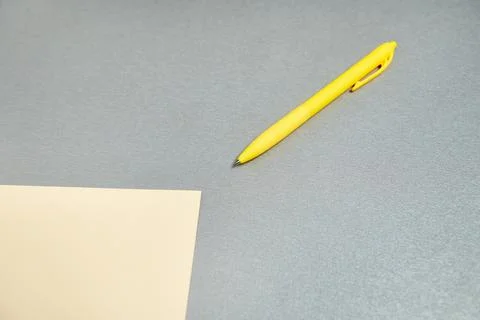 Flat lay of yellow pen lying near a designer paper on a gray surface Stock Photos