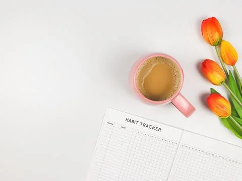 Flat layout of Habit tracker book, cup of coffee and tulips on white backgrou Stock Photos