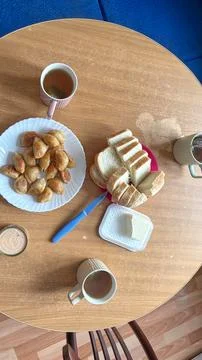 Flat layout of morning tea party with fresh bread, butter,on a wooden table. Stock Photos