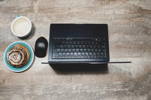 Flat layout of table with laptop, computer mouse, Cup of coffee and poppy bun Stock Photos