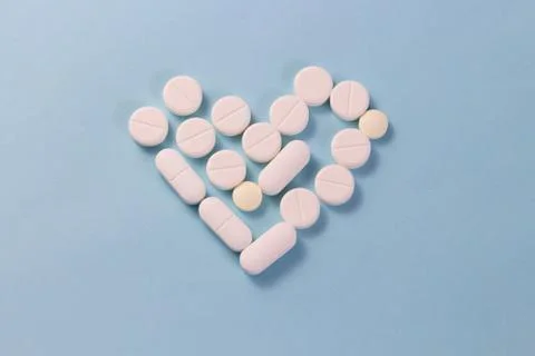 Flat layout white heart shaped pills isolated on blue background Stock Photos