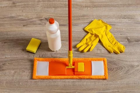 Flat mop and rubber gloves on the floor. Orange microfiber mop. Stock Photos