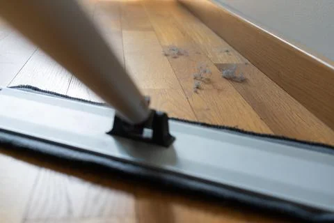 Flat mop cleaning dust gathered along a wooden floor Stock-Fotos