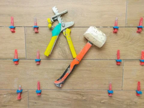 Flat pattern with red rubber hammer laying tile. Ceramic tile in wood style. Stock Photos