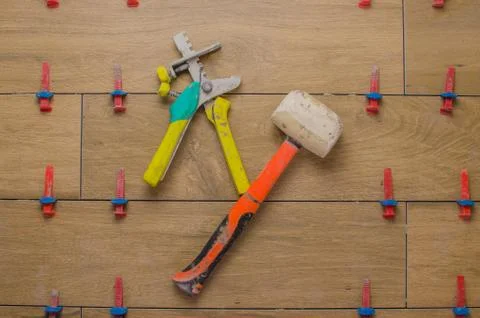 Flat pattern with red rubber hammer laying tile. Ceramic tile in wood style. Stock Photos