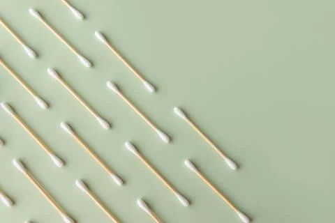 Flat plan of white cotton ear buds on green background with copy space Stock Photos