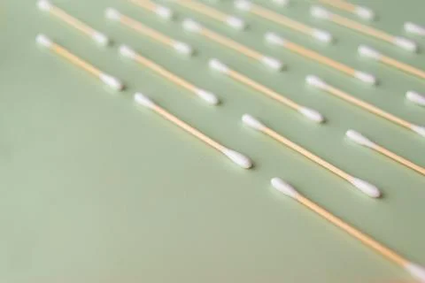 Flat plan of white cotton ear buds on green background with copy space Stock Photos