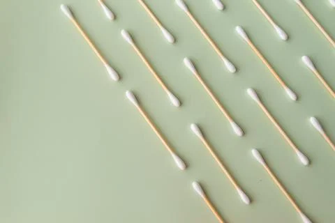 Flat plan of white cotton ear buds on green background with copy space Stock Photos