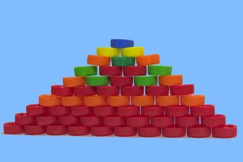 Flat pyramid of colored plastic bottle caps on the blue background Stock Photos