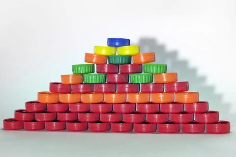 Flat pyramid made out of colored plastic bottle caps casts shadow in the sh.. Stock Photos