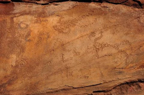 Flat red stone with ancient drawings of a hunting scene. Stock Photos