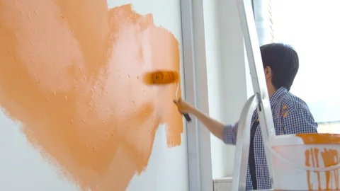 Flat renovation concept. Happy Middle-aged woman painting white wall with paint Stock Footage 127749415