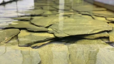 Flat rocks under clear water with ripples and reflections Stock Footage 314708591