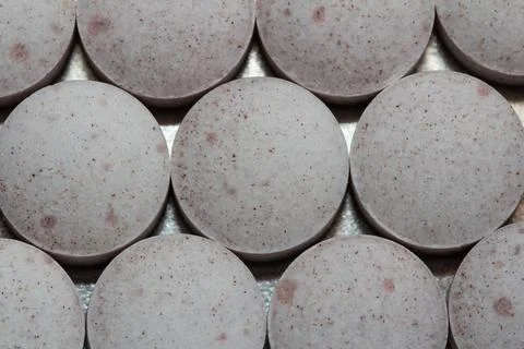 Flat, round tablets with speckled texture sit in rows Stock Photos
