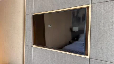 A flat screen television is mounted on a gray fabric wall paneling in a moder Stock Photos