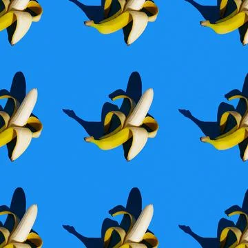 Flat seamless pattern of peeled bananas on a blue background Stock Photos