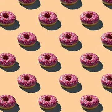 Flat seamless pattern of pink donuts on a warm background Stock Photos