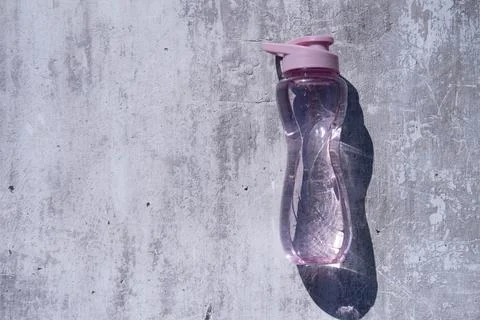 A flat shot of a plastic, reusable bottle of isotonic drink on a gray concret Stock Photos