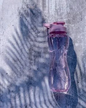 A flat shot of a plastic reusable bottle with an isotonic drink on a gray con Stock Photos