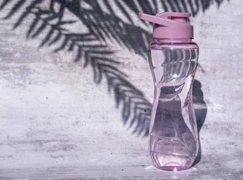 A flat shot of a plastic reusable bottle with an isotonic drink on a gray con Stock Photos