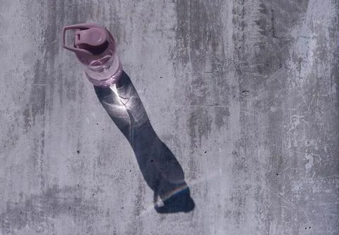 A flat shot of a plastic, reusable bottle of isotonic drink on a gray concret Stock Photos