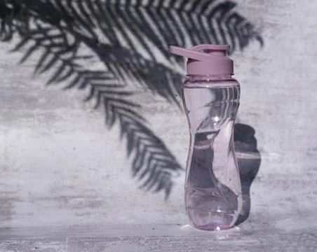 A flat shot of a plastic reusable bottle with an isotonic drink on a gray con Stock Photos