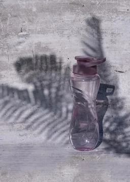 A flat shot of a plastic reusable bottle with an isotonic drink on a gray Stock Photos