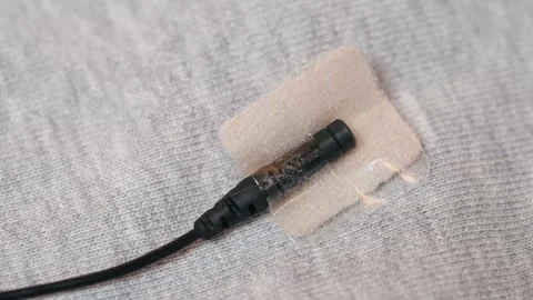 Flat shot of a wireless lavalier mic with fabric concealment patch on grey Stock Footage 282789836