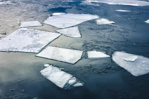 Flat slabs of ice floating on blue clear water Stock Photos