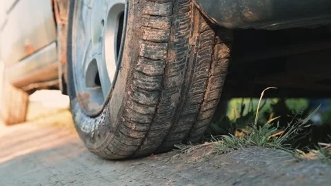 Flat tire on a car parked on a dirt road as the sun sets. Vidéo 344526221