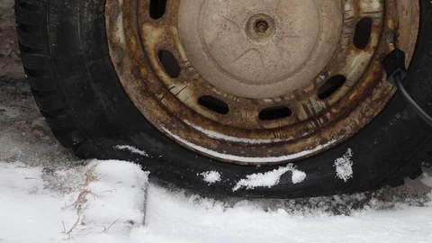 A flat tire of a car is quickly inflated by a compressor on white snow Stock Footage 122016030
