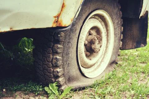 Flat tire on an old rusty SUV close-up. Stock Photos