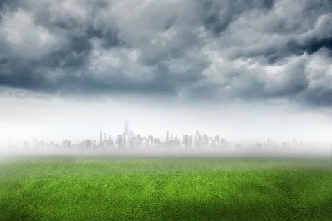 Flat vector art showing green grass field fading into mist with city skyline Stock Photos